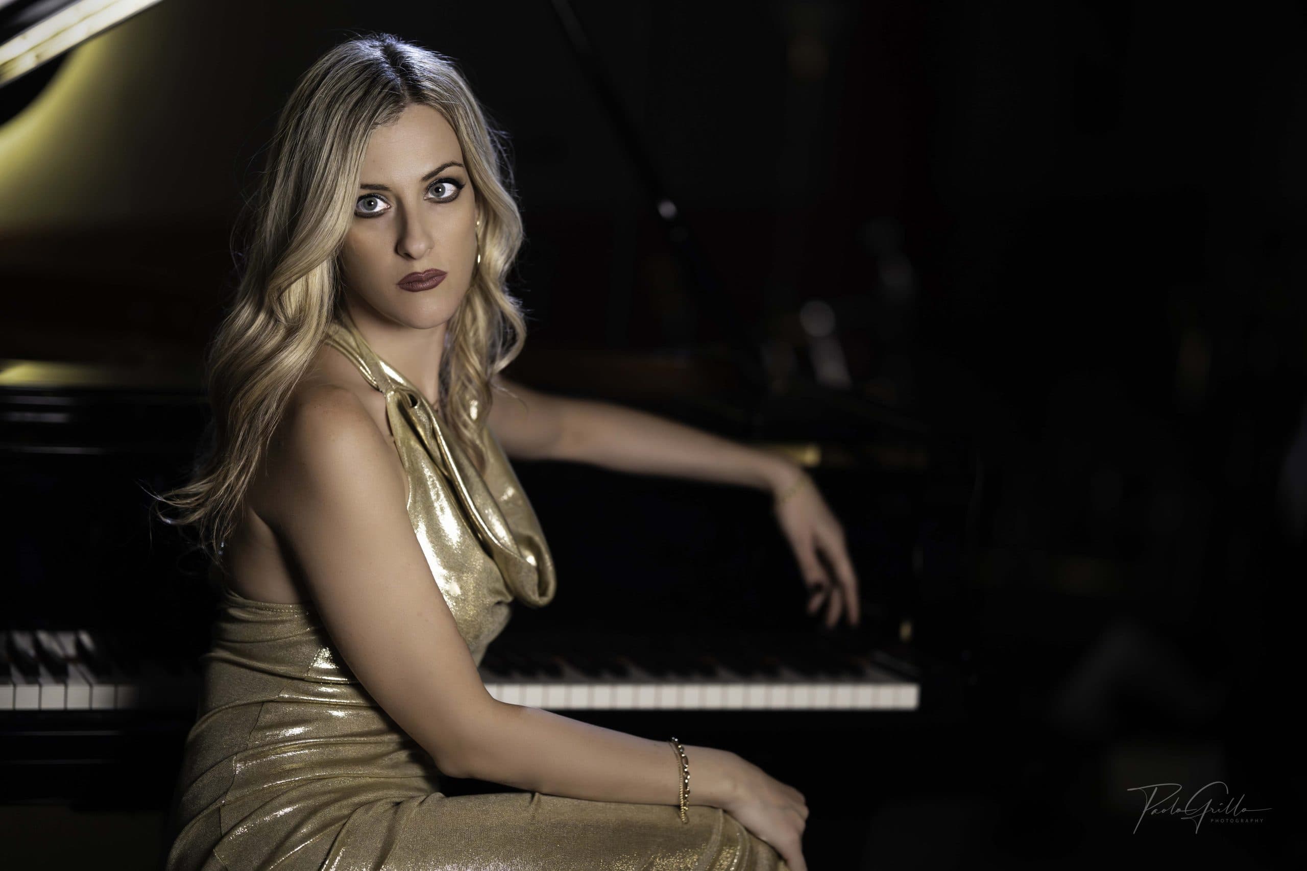 Francesca Tandoi, jazz pianist, in a gold dress seated at a grand piano